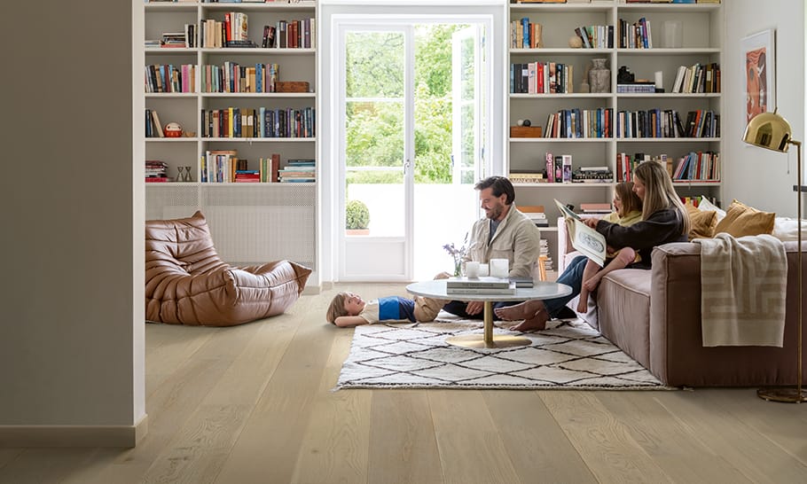 salon avec un sol en bois dur beige et une famille lisant dans un canapé